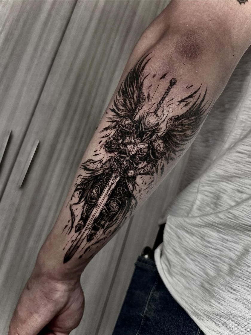 Arcángel con espada y alas desplegadas en el brazo
